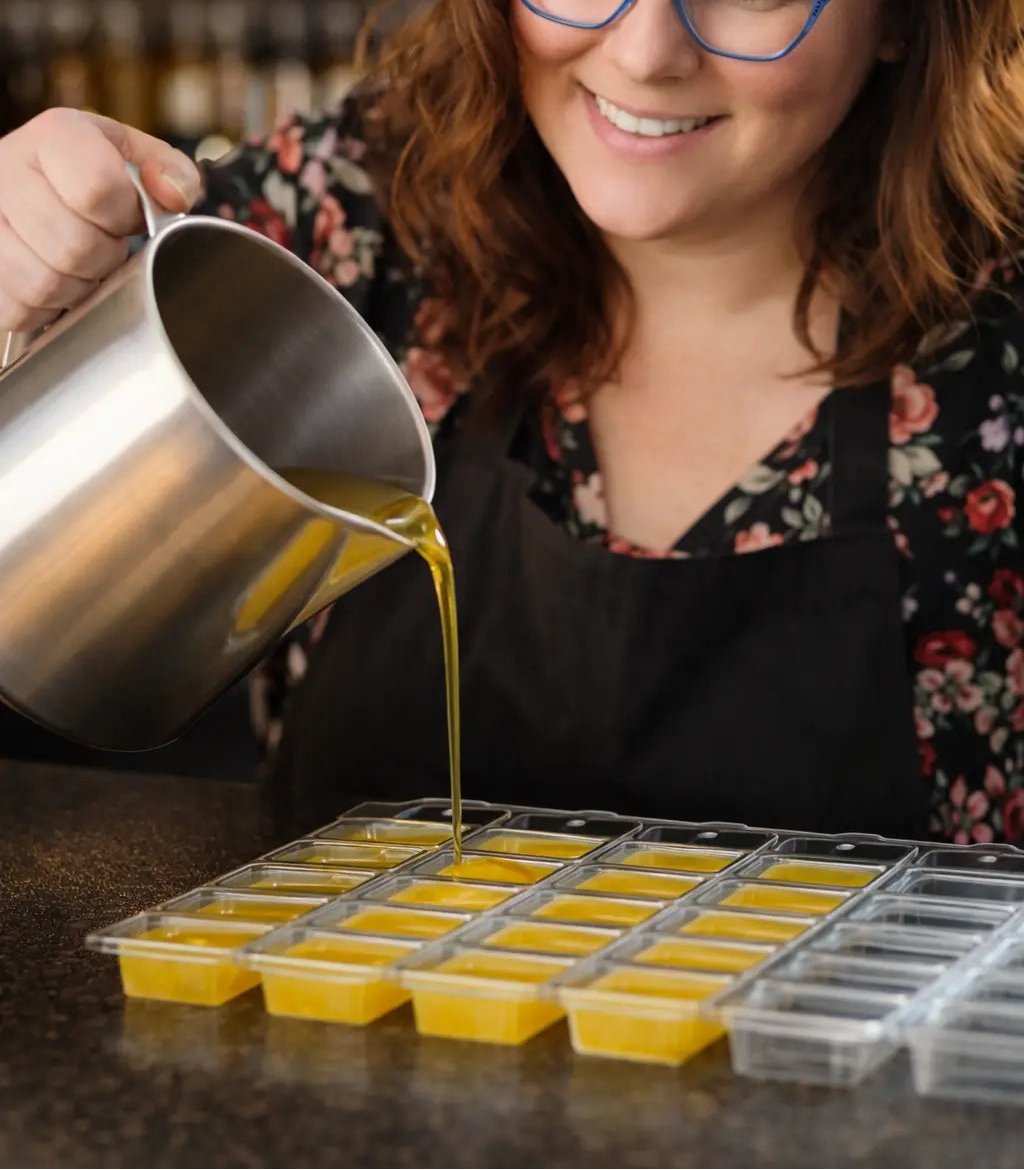 Woman pouring liquid into yellow molds on a dark surface